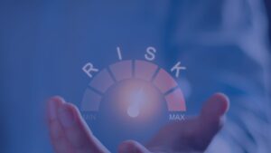 A conceptual gauge showing a hand measuring risk levels from minimum to maximum, representing invoice finance funding assessment factors.